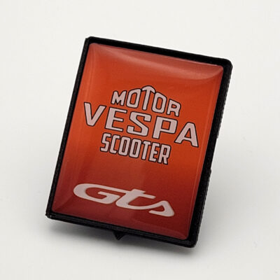 Oranges Vespa-Piaggio-Emblem mit weißem „Motor Vespa Scooter“-Schriftzug und GTS-Logo in glänzender 3D-Optik.
