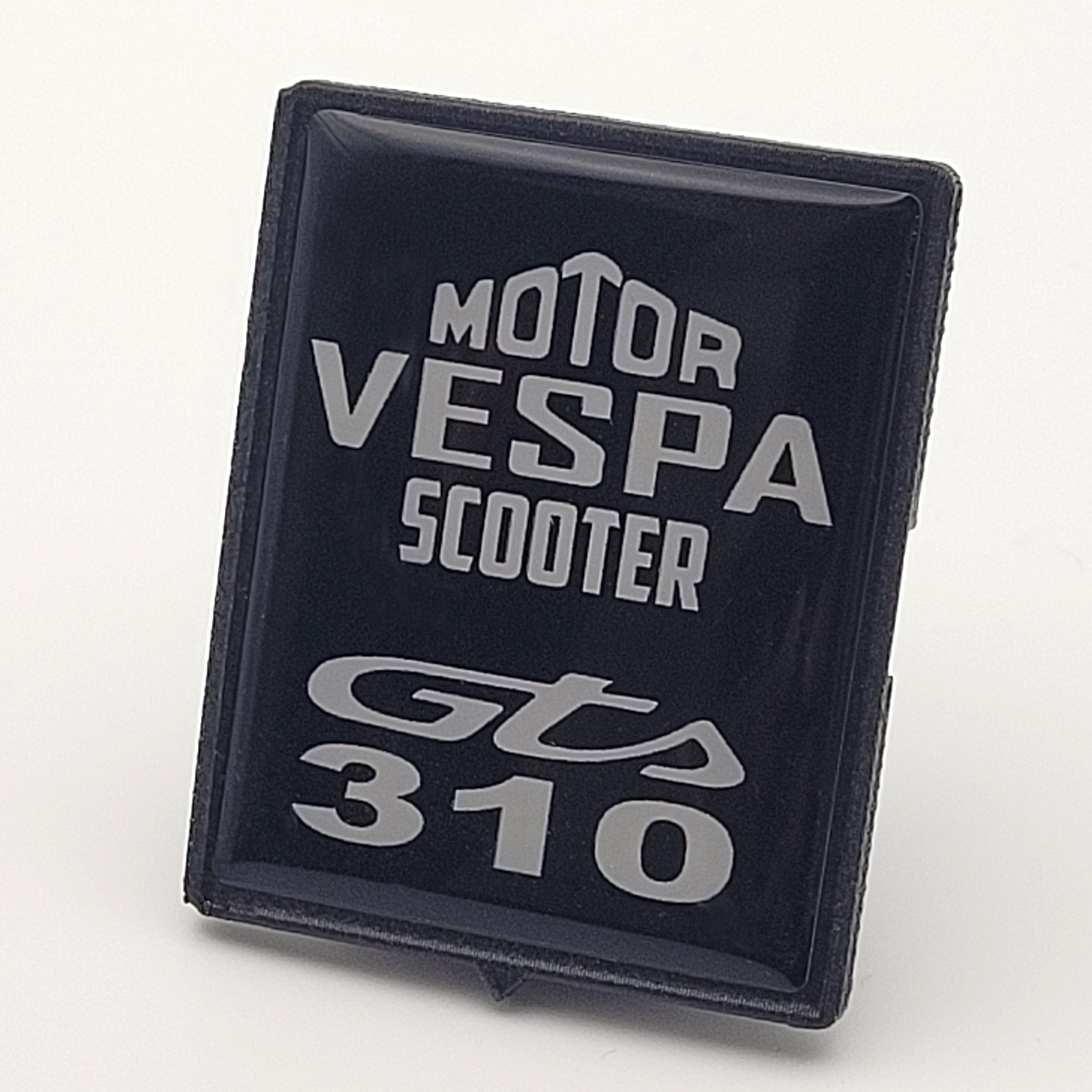 Fotografiertes schwarzes 3D Vespa Motor Scooter GTS 310 Emblem in schräger Ansicht mit silbernem Schriftzug und schwarzem Rand